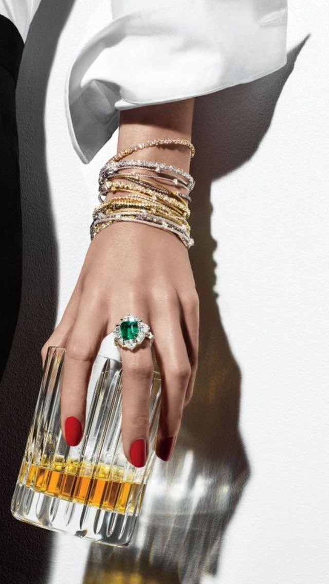 Emerald ring and bangles holding a crystal glass