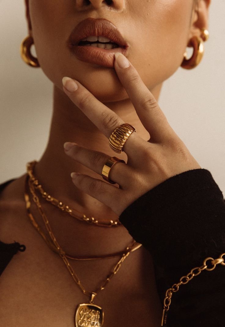 Gold rings and layered chains at the collarbone